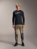 Alpinestars A-Dura Camo Pant, MTB Cycling Pants, Brown and Green Camouflage, worn with a black long-sleeve jersey and black shoes, sporty mountain bike style with durable stretch fabric