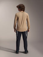 Alpinestars A-Dura Astar Langarmtrikot, Hellbraun, Rückansicht mit dem längeren abfallenden Saum, getragen mit einer schwarzen Hose mit Alpinestars-Branding, Performance-Mountainbike-Bekleidung