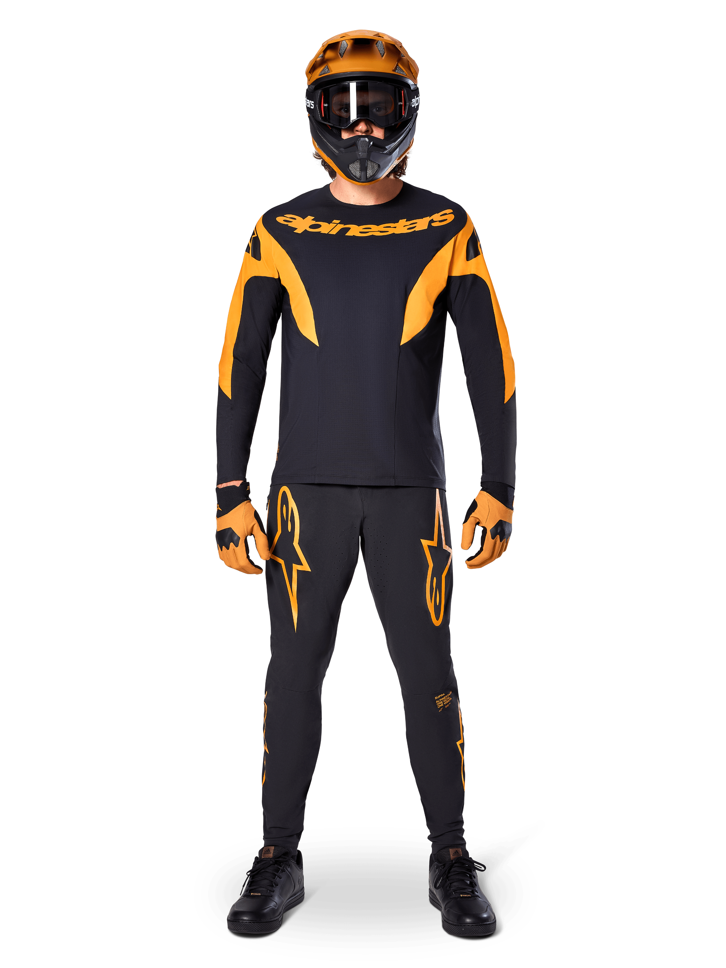 MTB rider wearing Alpinestars A-Supra Race Jersey - Long Sleeve in Black and Orange, matching black and orange pants, gloves, and a full-face helmet with goggles, coordinated mountain bike kit for racing and off-road performance