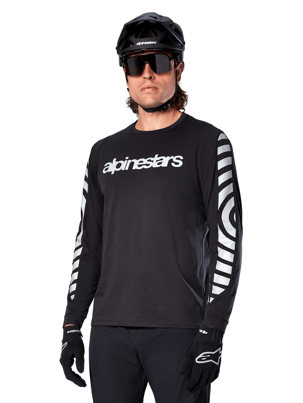 Alpinestars A-Dura Dri Oscar Langarmtrikot, MTB-Fahrradtrikot, Schwarz reflektierend, mit weißem Brust-Schriftzug und markanten reflektierenden kreisförmigen Grafiken auf den Ärmeln, getragen mit schwarzem Helm und Sonnenbrille, technische feuchtigkeitsableitende Bekleidung für Mountainbiking im Gelände