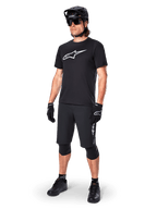 Mountainbike-Fahrer im Alpinestars A-Dura Dri Oscar Kurzarmtrikot in Schwarz Reflektierend, mit einem großen weißen Logo auf der Brust, kombiniert mit passenden schwarzen MTB-Shorts, Handschuhen und Helm, technische Radsportbekleidung für Offroad-Performance