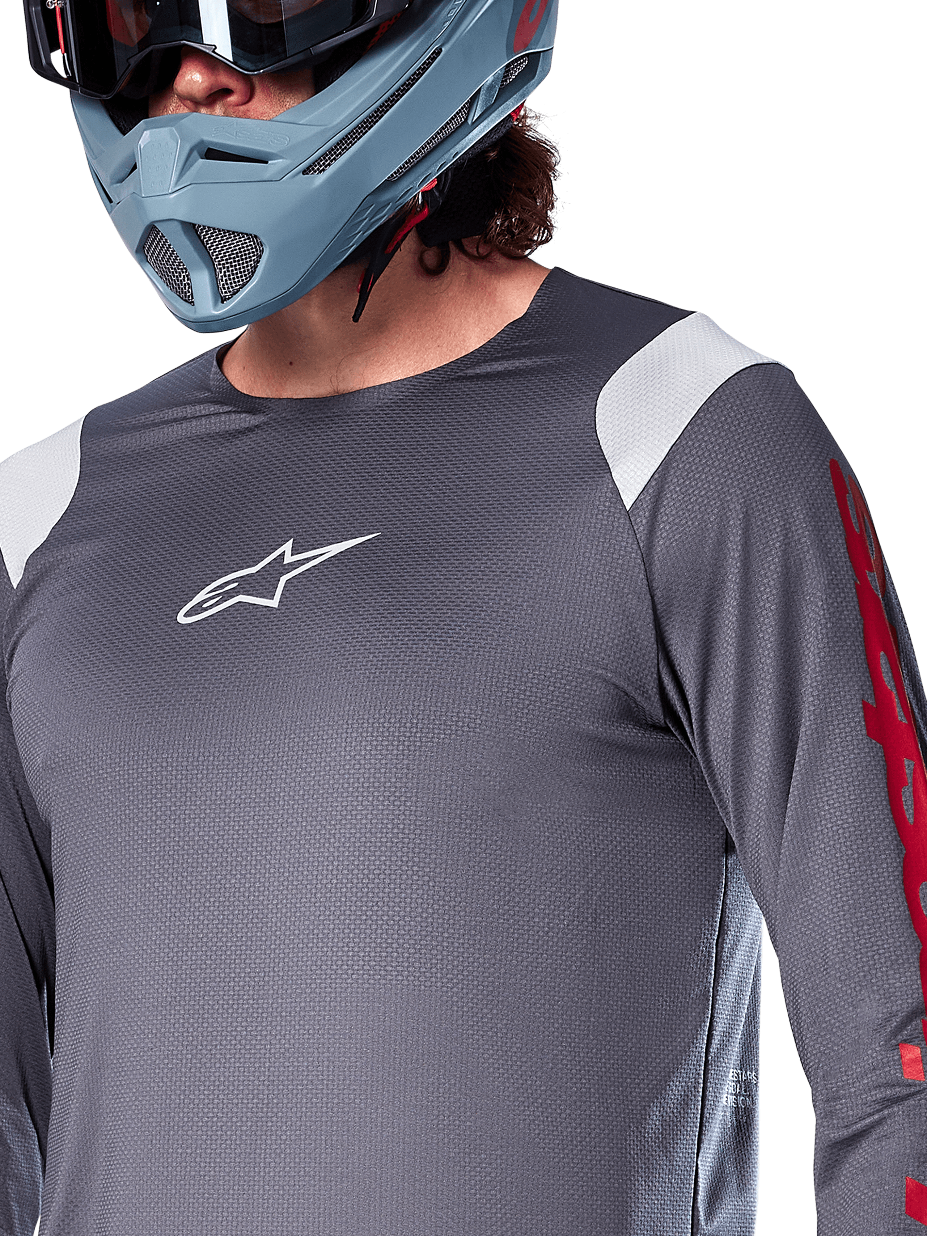 Alpinestars A-Supra Astar Long Sleeve Jersey, Dark Gray with white shoulder panels and red sleeve graphics, worn with a light blue-gray full-face helmet, performance mountain bike apparel