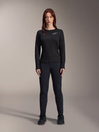 Alpinestars Stella A-Dura Thermo-Trikot, langärmeliges Damen-Mountainbike-Trikot in Schwarz, weißes Logo auf der Brust, kombiniert mit passender schwarzer Ausrüstung und Radschuhen, Studioporträt.