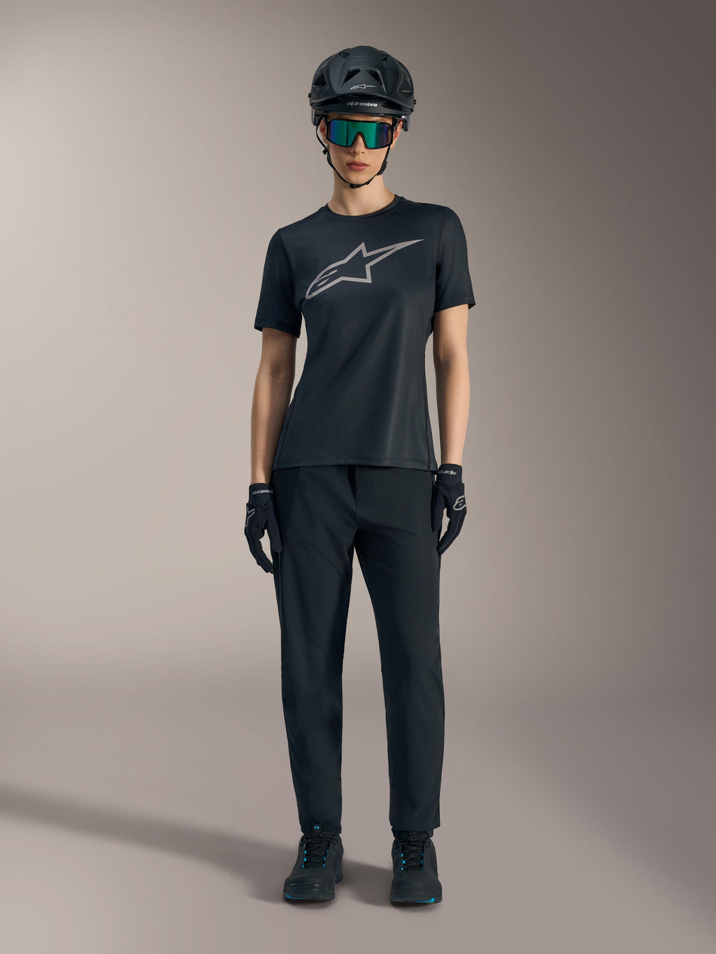 Stella A-Dura Ride Damen-Kurzarmtrikot in Schwarz mit silbernem Logo, kombiniert mit MTB-Hose und Helm.