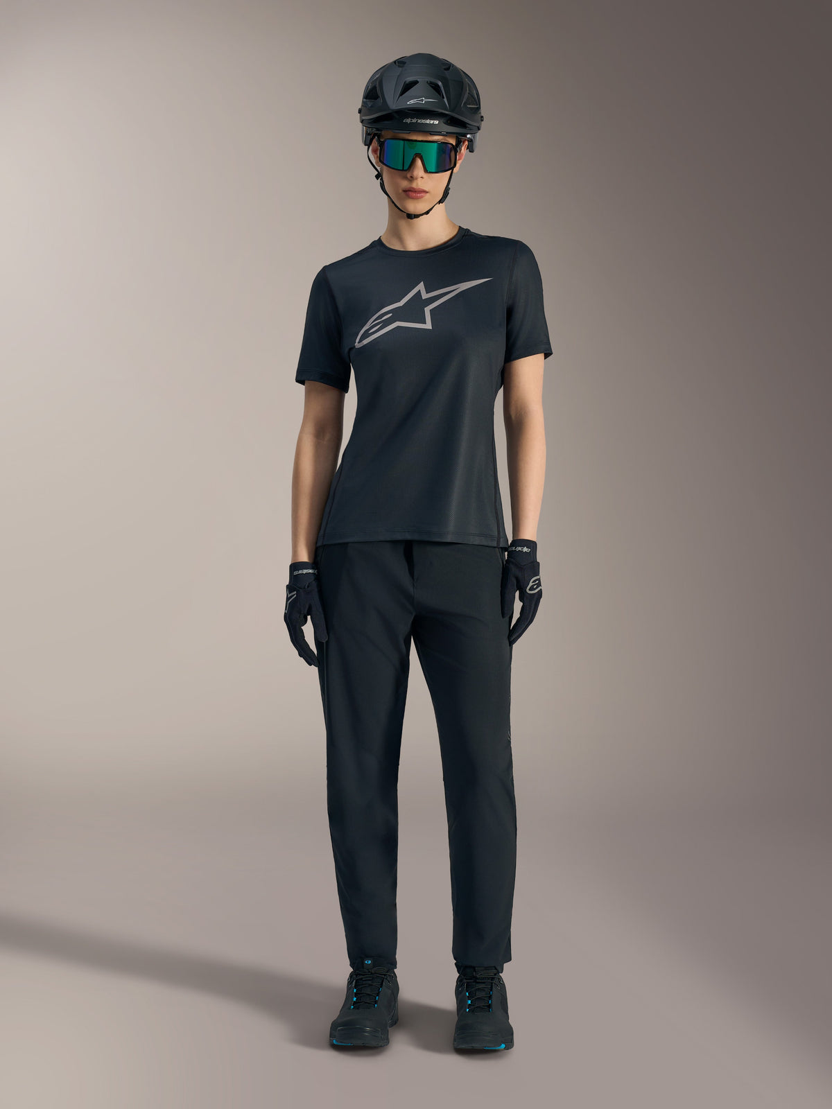 Stella A-Dura Ride Damen-Kurzarmtrikot in Schwarz mit silbernem Logo, kombiniert mit MTB-Hose und Helm.