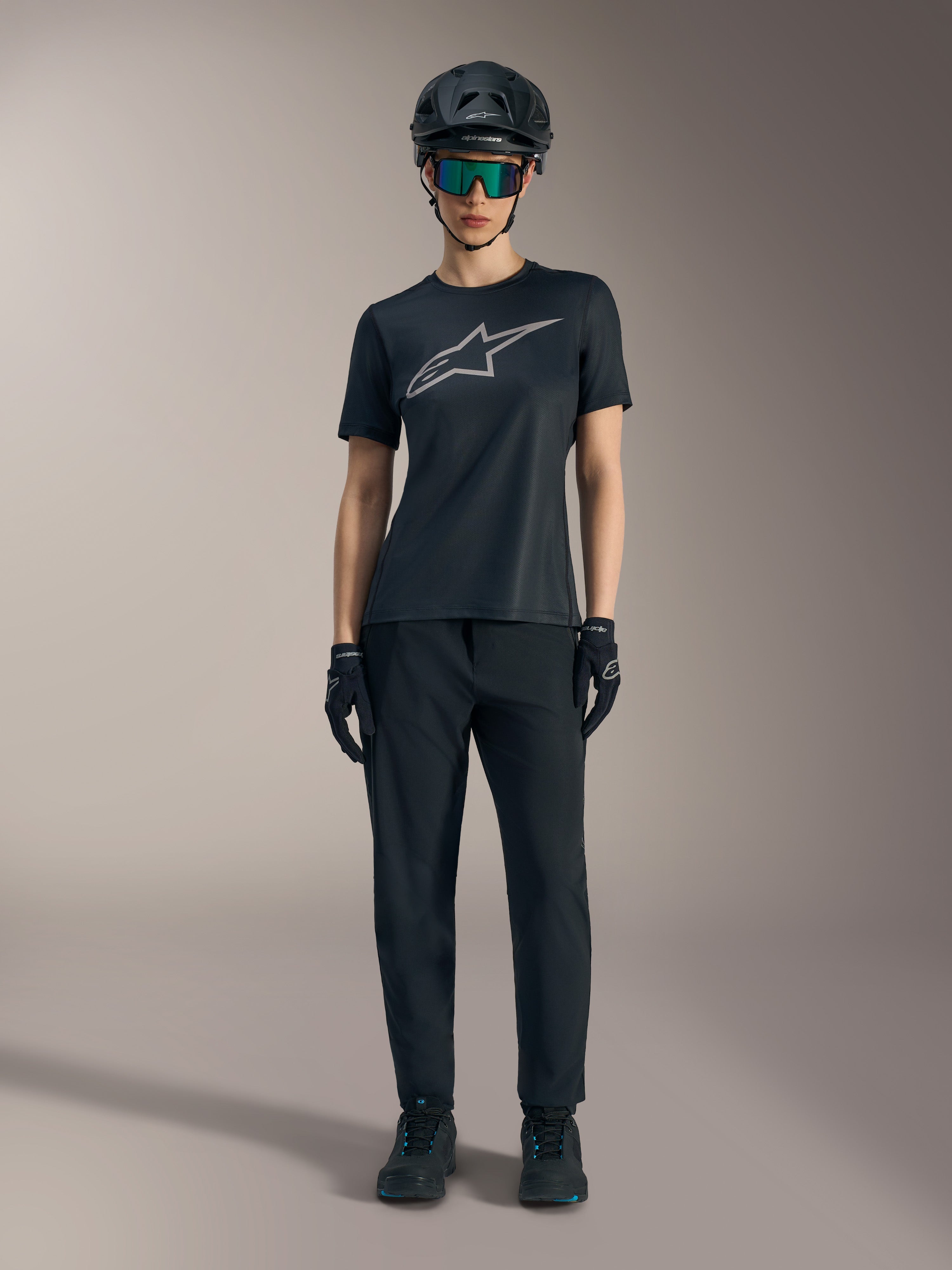 Stella A-Dura Ride Damen-Kurzarmtrikot in Schwarz mit silbernem Logo, kombiniert mit MTB-Hose und Helm.