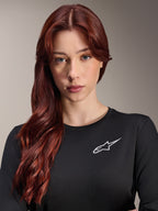 Alpinestars Stella A-Dura Thermal Jersey, Langarm-MTB-Trikot für Damen, Schwarz mit weißem A-Star-Logo auf der Brust, Nahaufnahme-Porträt einer Frau mit langen roten Haaren, Radbekleidung für kühles Wetter.