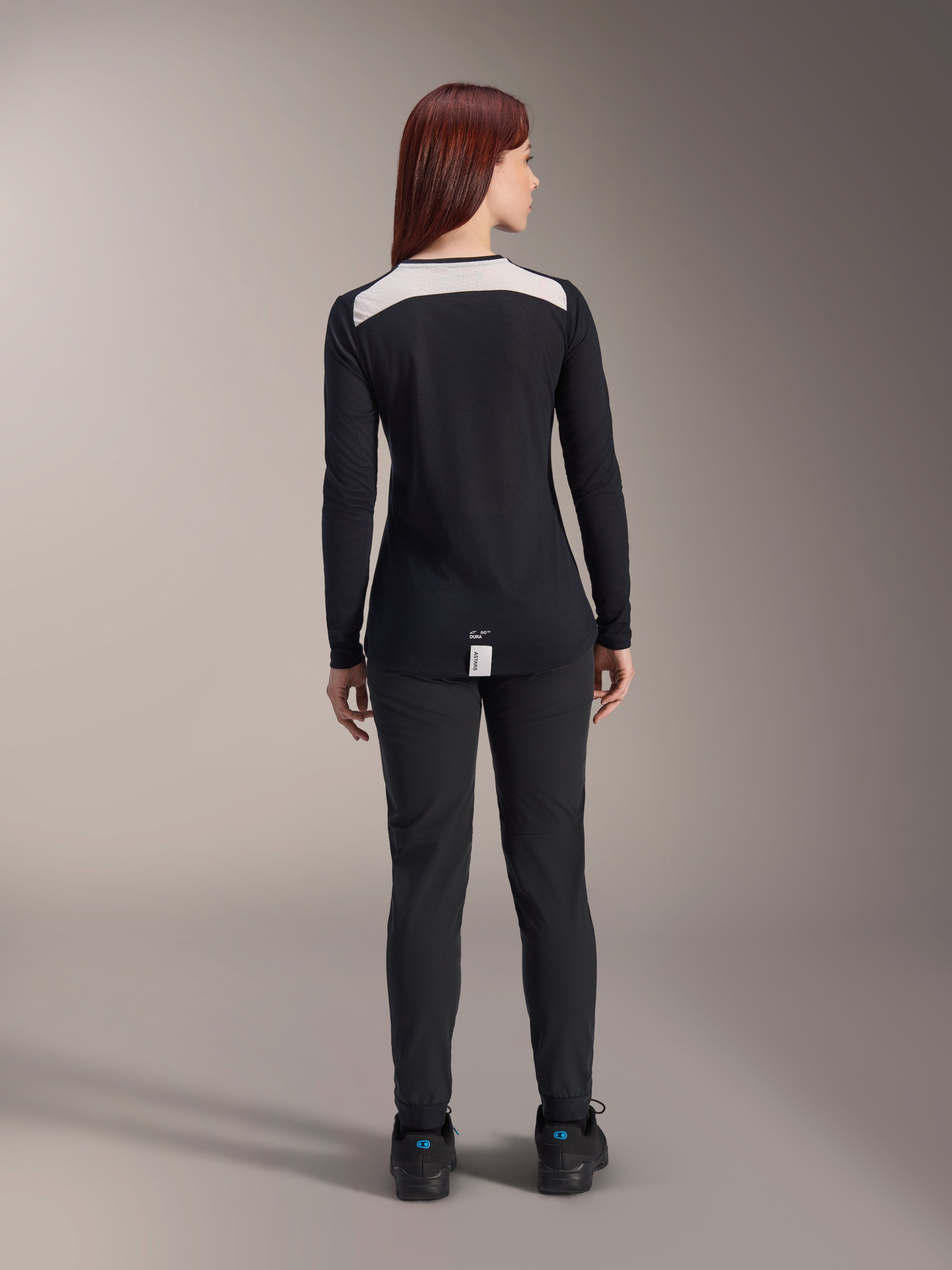 Alpinestars Stella A-Dura Dri Astar Langarmtrikot, Damen-MTB-Trikot, Schwarz, Rückansicht mit weißem Mesh-Belüftungseinsatz an den Schultern, kombiniert mit schwarzer Radhose, technische Offroad-Fahrbekleidung