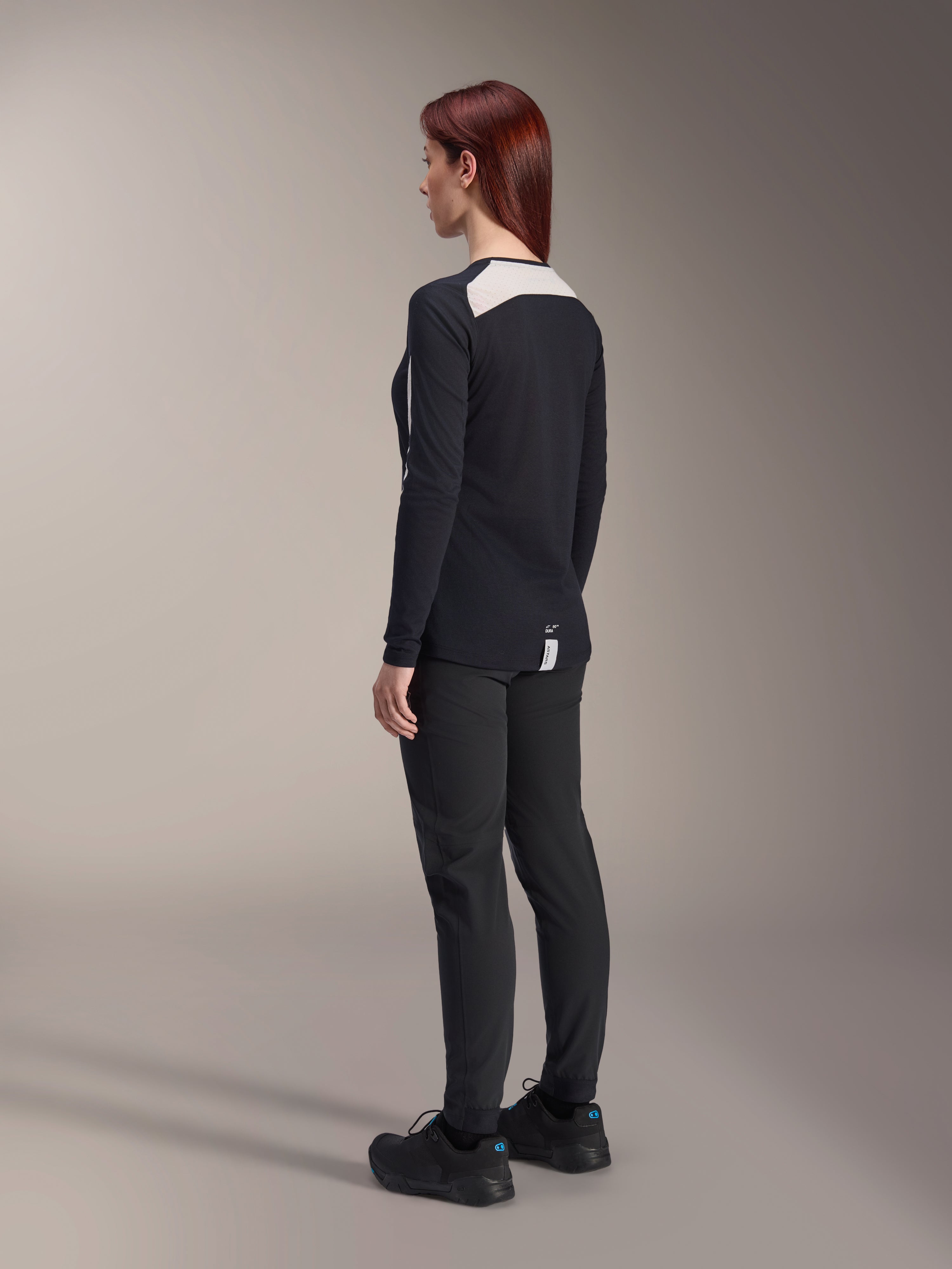 Alpinestars Damen Stella A-Dura Hose und Stella A-Dura Elite Trikot, Schwarz, Rückansicht mit weißen Mesh-Schultereinsätzen am langärmeligen Trikot, schmal geschnittene technische Hose, koordinierte Performance-Mountainbike-Ausrüstung.