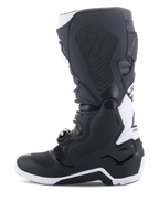 Alpinestars Tech 7 Enduro Drystar® Stiefel, Enduro-Motorradstiefel, Schwarz und Weiß, mediale Seitenansicht mit wabenförmig strukturierten Grip-Panels, TPU-Konstruktion und weißen Akzenten an Ferse und oberem Wadenbereich, professionelles Offroad-Schuhwerk