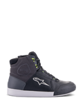 Alpinestars Chrome Drystar Schuhe, urbane Motorrad-Sneaker in Schwarz, Dunkelgrau und Gelb Fluo, mit hochwertigen Leder- und Wildledereinsätzen, weißer Sohle, neongelben Schnürsenkeln und markantem Stern-Logo.