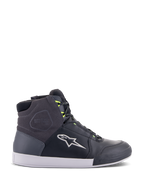 Alpinestars Chrome Drystar Schuhe, urbane Motorrad-Sneaker in Schwarz, Dunkelgrau und Gelb Fluo, mit hochwertigen Leder- und Wildledereinsätzen, weißer Sohle, neongelben Schnürsenkeln und markantem Stern-Logo.