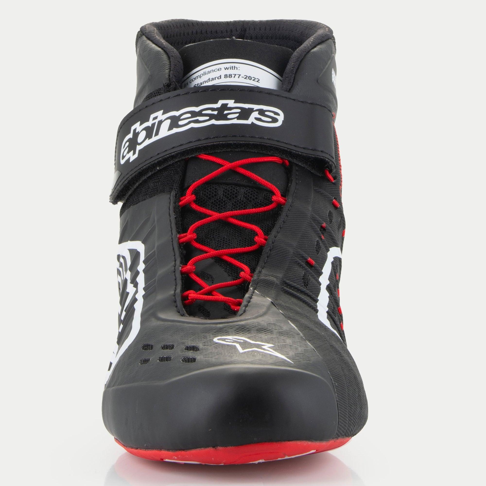 Alpinestars Tech-1 KX V3 Schuhe, Karting-Schuhe, Schwarz Weiß und Rot, Vorderansicht mit roter asymmetrischer Schnürung, schwarzem Klettverschluss-Knöchelriemen mit weißem Branding und auf der Zunge sichtbarem FIA 8877-2022 Zertifizierungsetikett.