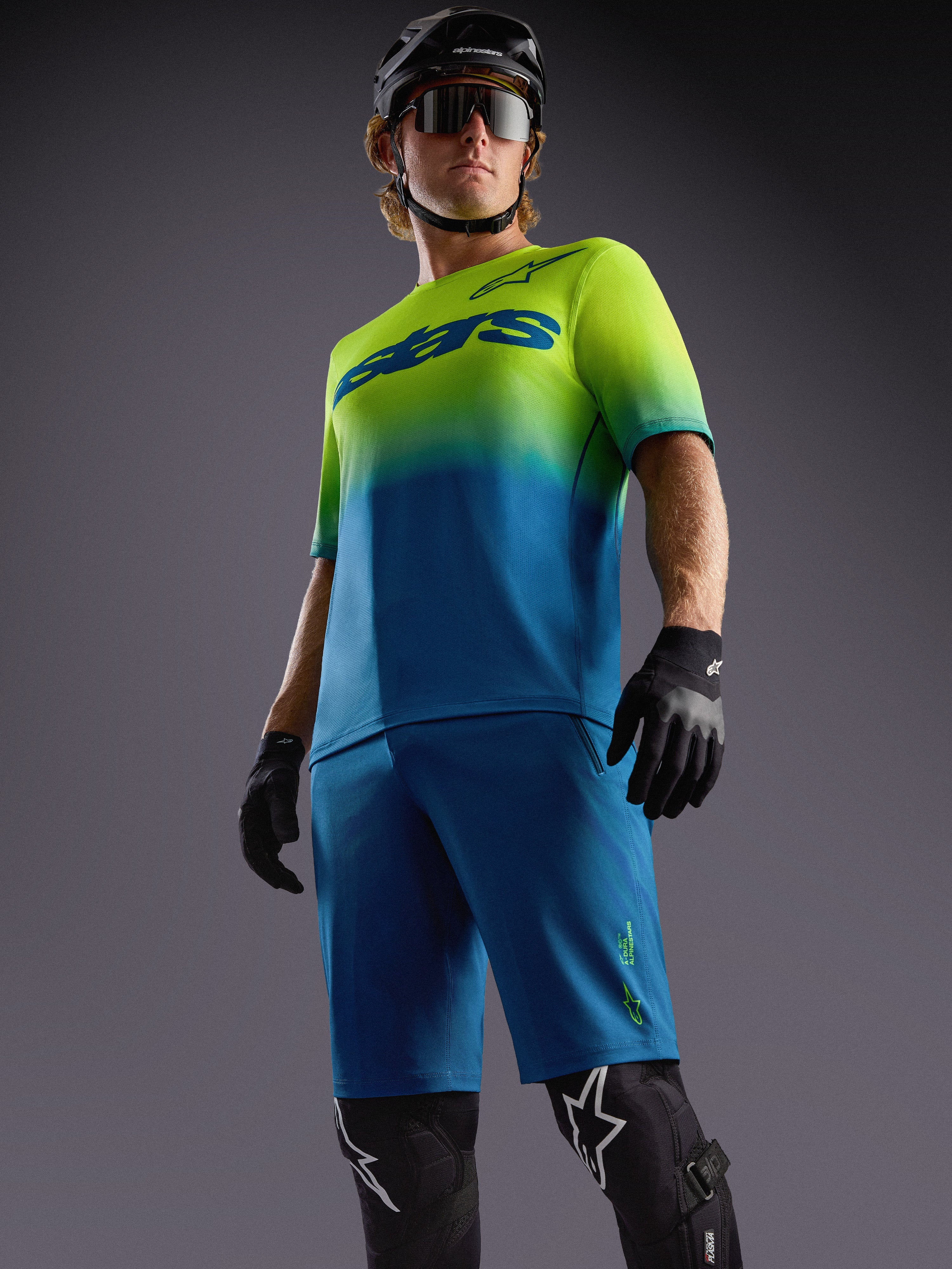 A-Dura ASTARS Jersey 2.0, blau-gelbes Kurzarm-MTB-Trikot mit Farbverlauf, passenden Shorts und Protektoren.
