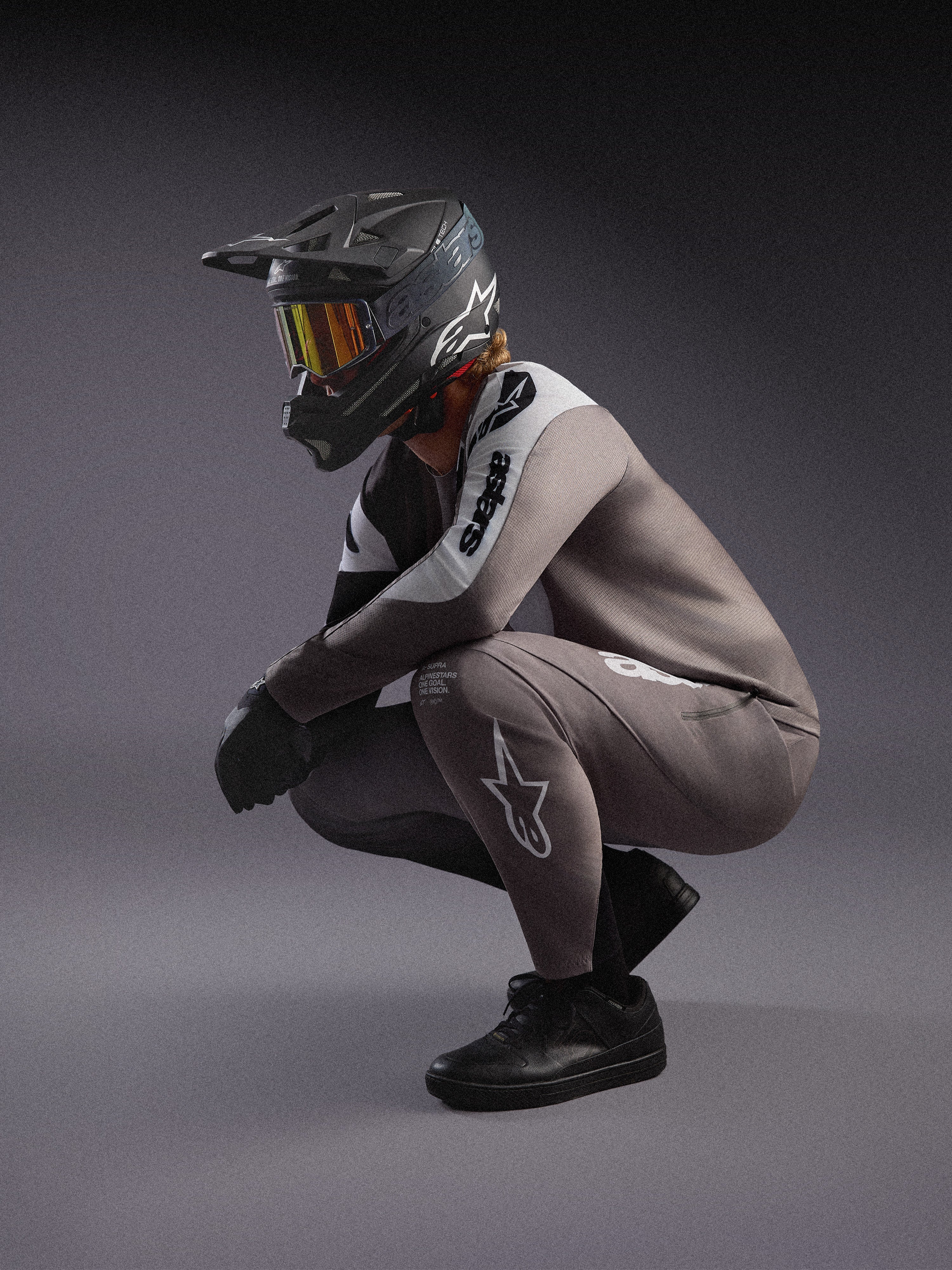 A-Supra Elite MTB-Trikot und Hose in Grau mit Farbverlauf, schwarzer Fullface-Helm und Goggles für den Rennsport.