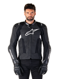 Alpinestars Missile V3 Lederjacke, Schwarz mit weißen Logos, getragen von einem Modell mit schwarzen Motorradhandschuhen, hochwertige Motorrad-Rennjacke aus Leder mit perforierten Belüftungseinsätzen und Performance-Fahrfunktionen