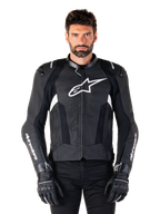 Alpinestars Missile V3 Lederjacke, Schwarz mit weißen Logos, getragen von einem Modell mit schwarzen Motorradhandschuhen, hochwertige Motorrad-Rennjacke aus Leder mit perforierten Belüftungseinsätzen und Performance-Fahrfunktionen