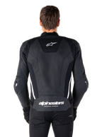 Rückansicht der Alpinestars Missile V3 Lederjacke in Schwarz und Weiß, mit dem Alpinestars-Sternlogo auf dem oberen Rücken und Markenschriftzug im Lendenbereich, weißen vertikalen Streifen und externen Ellbogenschleifern, erstklassige Rennsport-Lederjacke.