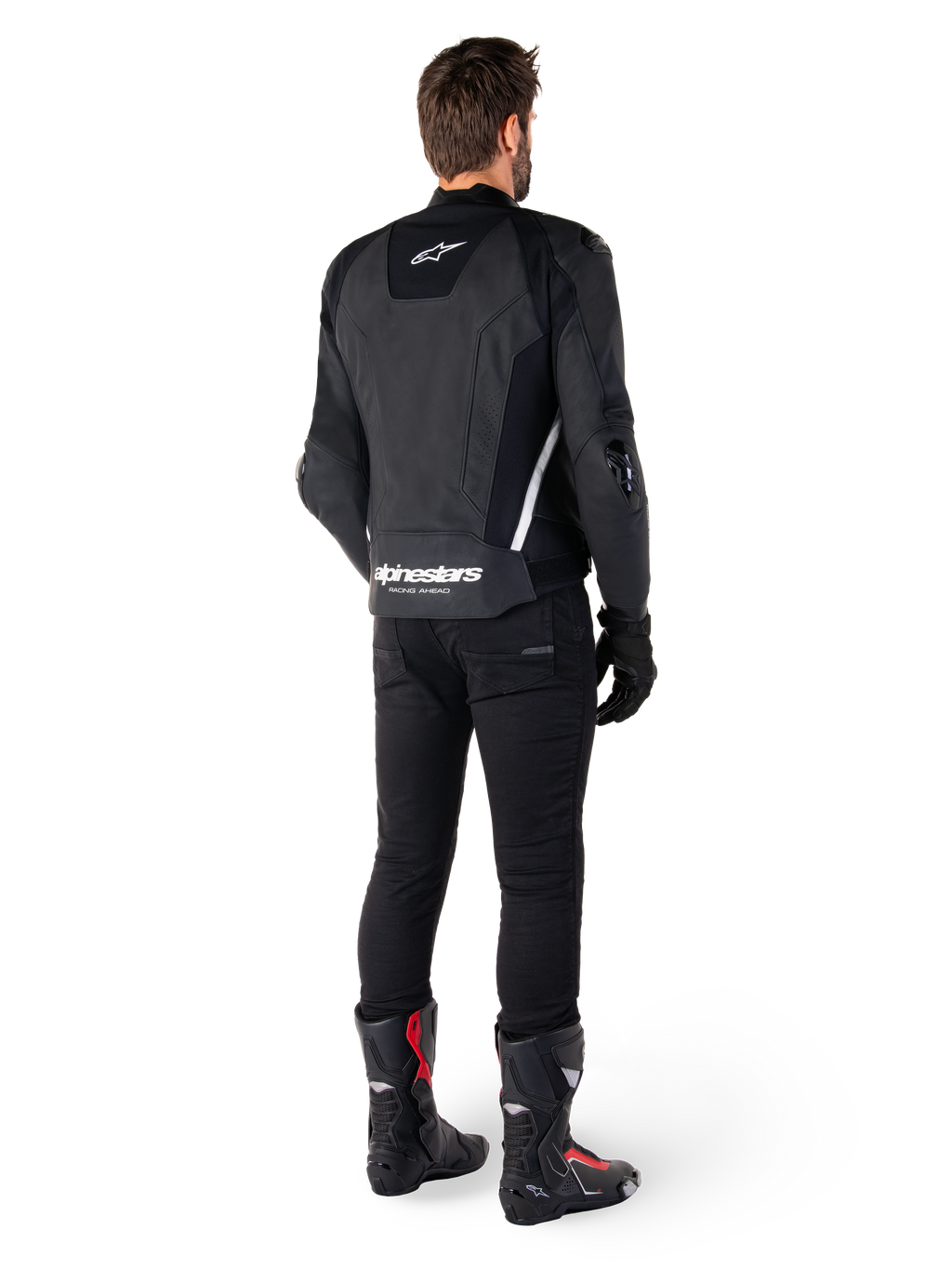 Alpinestars Missile V3 Lederjacke, Schwarz und Weiß, Rückansicht am Fahrer, mit markantem weißem Alpinestars-Schriftzug am unteren Rücken und kleinem Logo am oberen Rücken, getragen mit schwarzer Hose und Rennstiefeln, hochwertige Lederkonstruktion für Motorradrennen