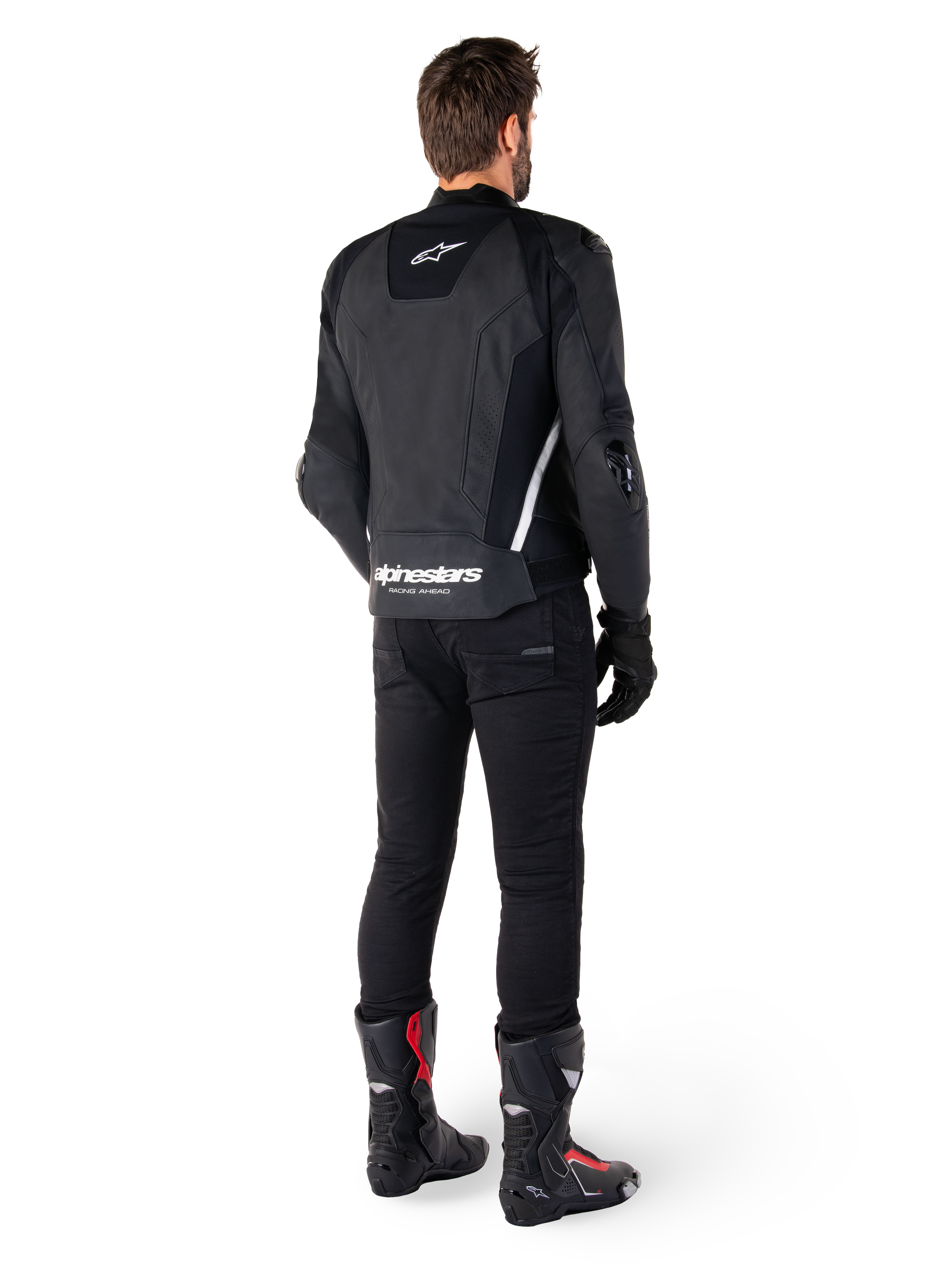 Alpinestars Missile V3 Lederjacke, Schwarz und Weiß, Rückansicht am Fahrer, mit markantem weißem Alpinestars-Schriftzug am unteren Rücken und kleinem Logo am oberen Rücken, getragen mit schwarzer Hose und Rennstiefeln, hochwertige Lederkonstruktion für Motorradrennen