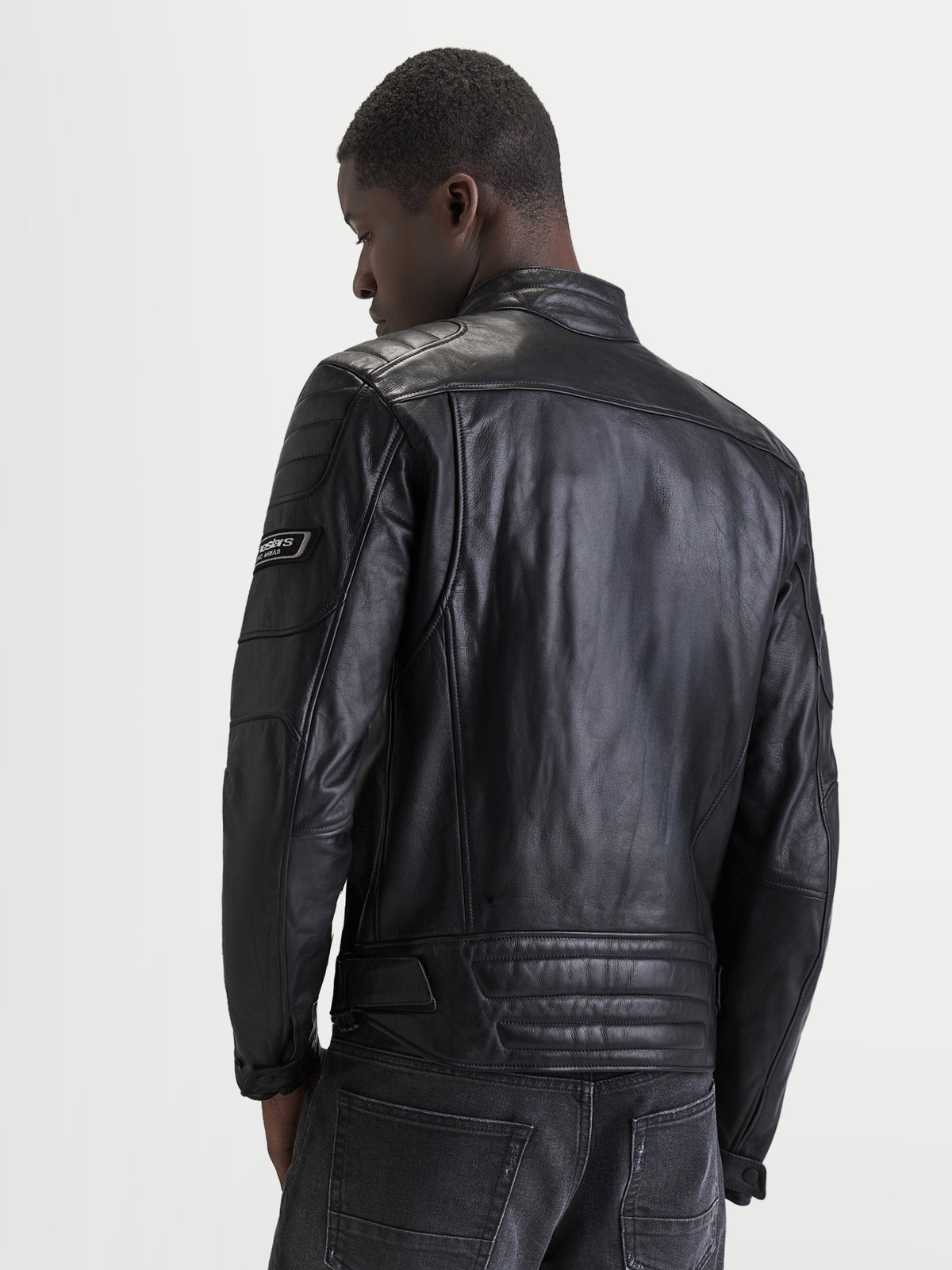 Alpinestars Revern Leather Jacket, men's black leather motorcycle jacket, rear view on a model showing distressed full-grain bovine leather construction, classic biker collar, and heritage-style branding details