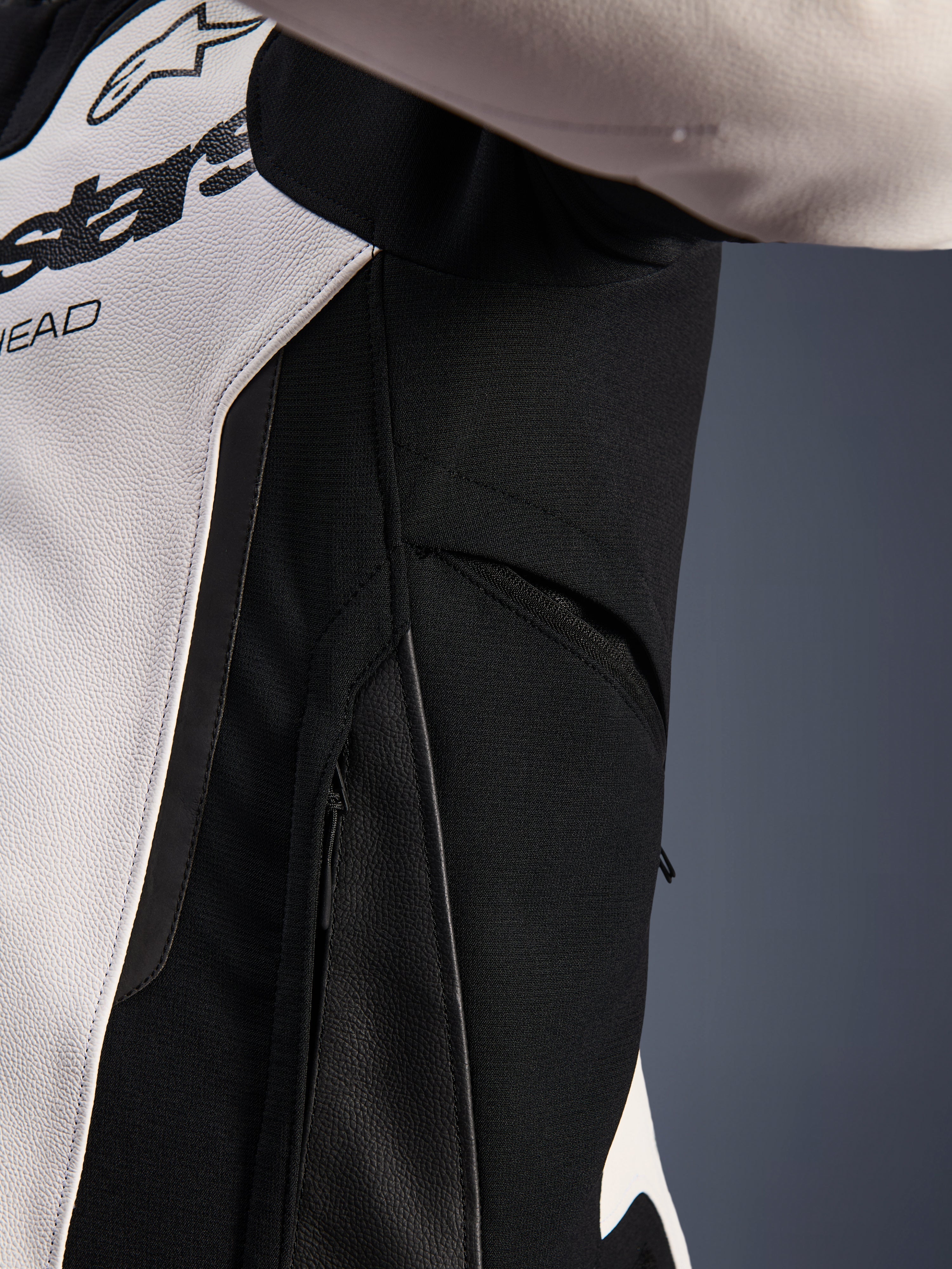 Close-up detail of the Alpinestars GP Force V2 Leather Jacket in White and Black, highlighting the zippered side ventilation and high-resistance stretch fabric panels for enhanced airflow and rider mobility.