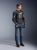Alpinestars GP Plus R V4 Rideknit Lederjacke, Schwarz und Weiß, Motorrad-Lederjacke getragen von einem Modell mit blauen Jeans und schwarzen Handschuhen, mit einem markanten weißen Astars-Logo auf der Brust, perforierten Paneelen und weißen Akzenten an den Schultern.