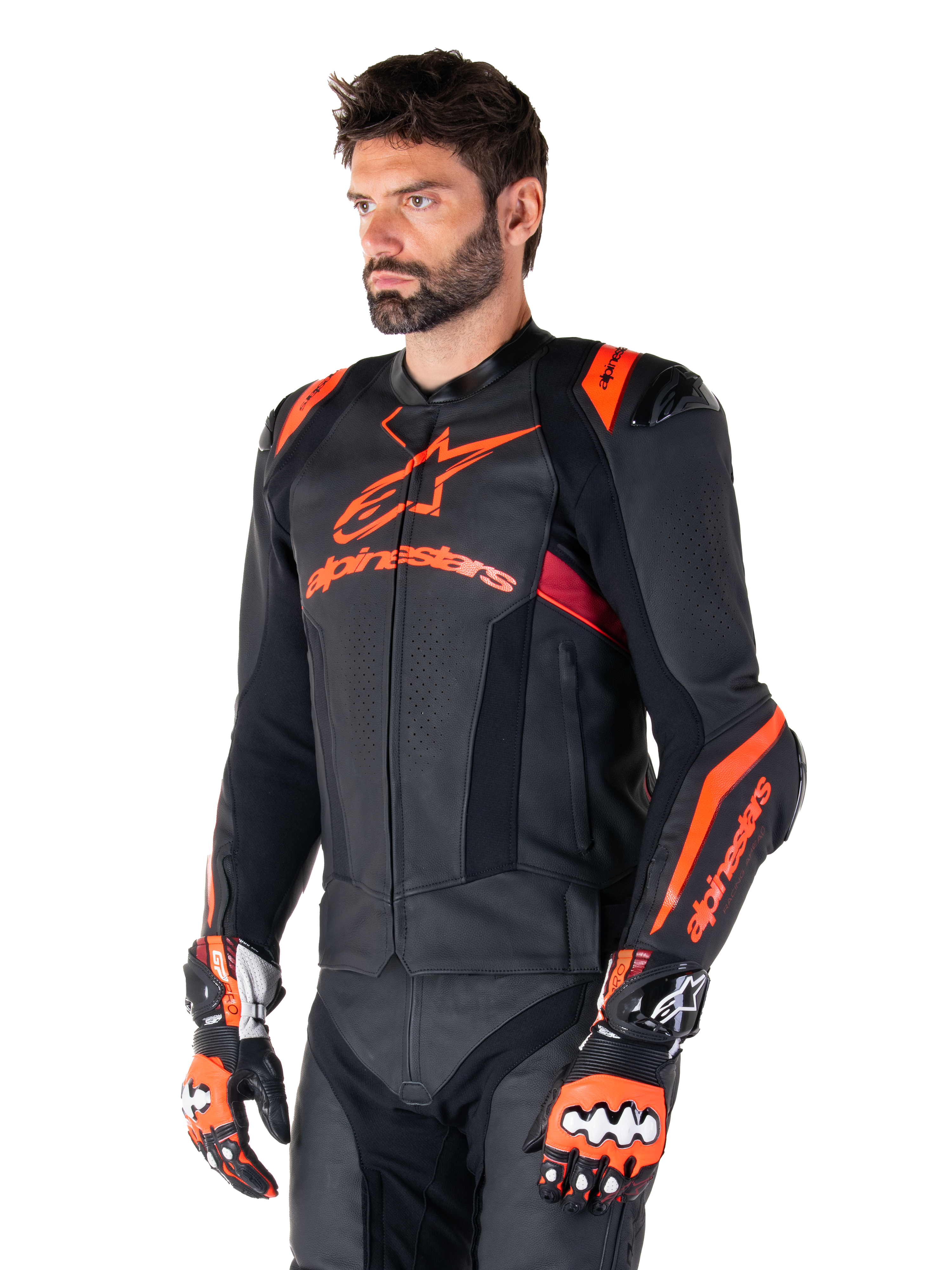 Alpinestars Missile V3 Ignition Lederjacke, Schwarz mit Akzenten in Red Fluo und Dark Red, getragen von einem männlichen Model mit passenden Rennhandschuhen und Lederhose, mit auffälligem Alpinestars-Branding, perforierten Ledereinsätzen und externen Schulterprotektoren, professionelle Motorrad-Rennausrüstung