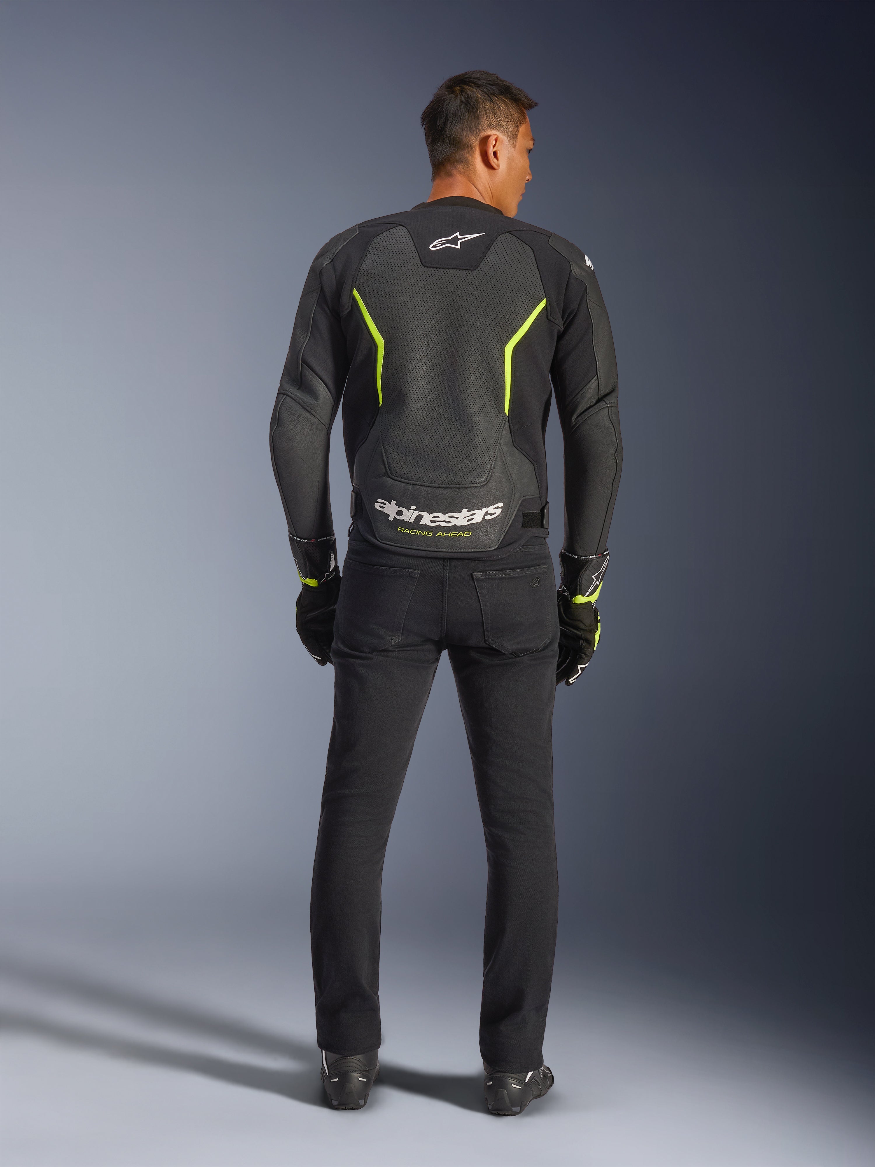 Alpinestars GP Force V2 Air Leather Jacket, Black and Yellow Fluo, back view of model wearing the sport motorcycle jacket, featuring large perforated sections, neon yellow accents, and white 'alpinestars' branding on the lower back, paired with black riding gear