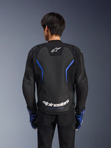 Alpinestars GP Force V2 Airflow Lederjacke, Schwarz Metallic-Blau, Rückansicht, mit einem großen perforierten Rückenpanel zur Belüftung, blauen Akzenten und weißem Alpinestars-Branding, getragen mit passenden blauen Handschuhen und schwarzer Hose für sportliches Fahren.