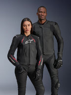 Alpinestars Dusk Airflow und Stella Dusk Lederjacken, männliche und weibliche Fahrer in schwarzen Motorrad-Lederjacken, Herrenjacke mit perforiertem Leder für Belüftung, Damenjacke mit roten Akzenten und weißen Logos, kombiniert mit schwarzen Motorradhosen und Handschuhen, sportliche Performance-Fahrbekleidung
