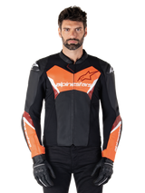 Alpinestars Faster V3 Lederjacke, Sport-Motorradjacke, Schwarz und Rot Fluo, getragen von einem männlichen Model mit schwarzen Motorradhandschuhen und -hosen, mit markantem Alpinestars-Branding auf Brust und Unterarmen, hochwertige Lederkonstruktion für den Straßeneinsatz.