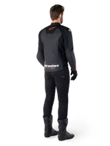 Alpinestars Faster V3 Lederjacke, Sport-Motorradjacke, Schwarz und Rot Fluo, Rückansicht getragen mit schwarzer Hose und schwarzen Stiefeln, mit „alpinestars RACING AHEAD“-Schriftzug am unteren Rücken und einem kleinen roten Stern-Logo, schlanke Lederkonstruktion in sportlicher Passform