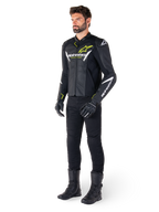 Männlicher Fahrer mit der Alpinestars Faster V3 Airflow Lederjacke in Schwarz, Weiß und Neongelb, kombiniert mit schwarzer Motorradhose und Stiefeln, mit perforierten Ledereinsätzen, weißen Logo-Details und neongelben Akzenten, professionelle Sport-Fahrerausrüstung