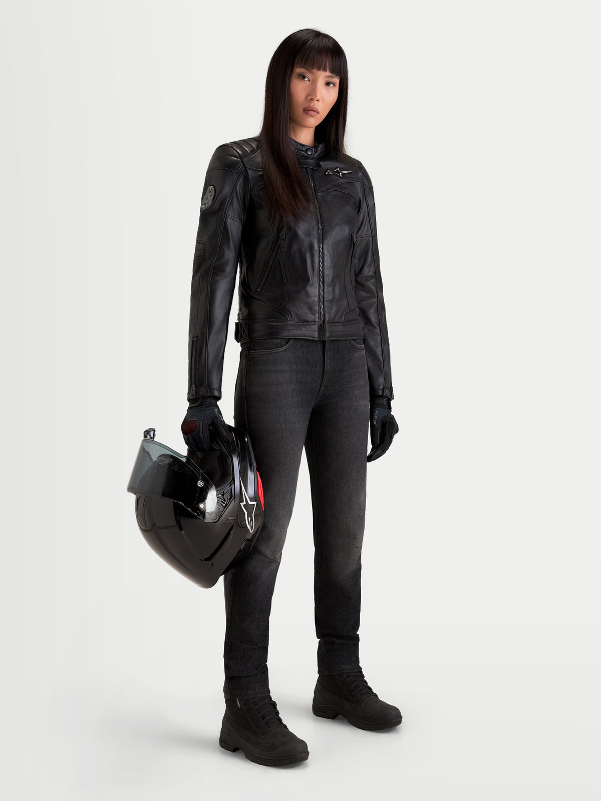 Alpinestars Revea Damen Lederjacke, urbane Motorrad-Lederjacke für Damen in Schwarz, Vollnarbenleder-Konstruktion an weiblichem Model mit Helm