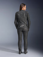 Alpinestars Woman Stella Dusk Leather Jacket, Black, Rear view featuring white Alpinestars logo on the lower back and 'DUSK' branding on the upper back, worn with black riding pants and boots, showcasing the contoured women's fit and protective leather construction.