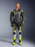 Alpinestars GP Tech V5 einteiliger Lederkombi, professioneller Motorrad-Rennanzug in Schwarz und Neongelb Fluo mit weißen Akzenten, getragen von einem Modell mit passenden Rennhandschuhen und Stiefeln, mit aerodynamischem Design und Schutz-Slidern.