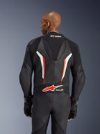 Alpinestars GP Force V2 Lederkombi, 1-teiliger Motorradanzug, Schwarz, Weiß und Fluo-Rot, Rückansicht des Oberkörpers zeigt perforiertes Leder und Tech-Air Ready-Logo, getragen mit passenden schwarz-roten Handschuhen