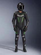 Motorradrennfahrer in Alpinestars GP Force V2 Lederkombi - 1-Teiler in Schwarz und Grün, kombiniert mit Carbon-Helm und Rennhandschuhen, mit perforierten Lederpaneelen und weißen Alpinestars-Logos, professionelle Ausrüstung für Rennstrecke und sportliches Fahren