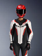 Alpinestars GP Force V2 Lederkombi - 1-teilig, Weiß Schwarz Rot Fluo, getragen mit rotem Integralhelm und schwarzen Rennhandschuhen, mit perforierten Lederbahnen und markantem Alpinestars-Branding auf der Brust, professionelle Performance-Ausrüstung für Motorradrennen