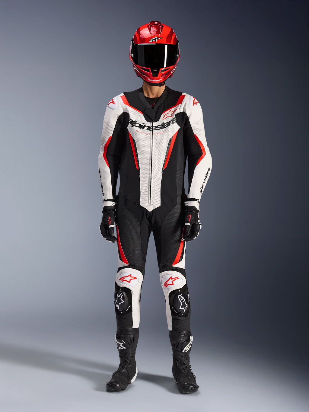 Alpinestars GP Force V2 Lederkombi – 1-teilig, Weiß, Schwarz und Rot Fluo, komplette Rennausrüstung inklusive rotem Helm, schwarzen Handschuhen und Stiefeln, mit aerodynamischem Design und Alpinestars-Branding auf Brust und Knien