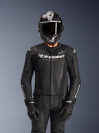 Rider wearing Alpinestars GP Force V2 2-Piece Leather Suit in Black, perforated leather construction with white 'Racing Ahead' chest logo, silver and carbon fiber full-face helmet, black gloves, professional sport and track riding gear