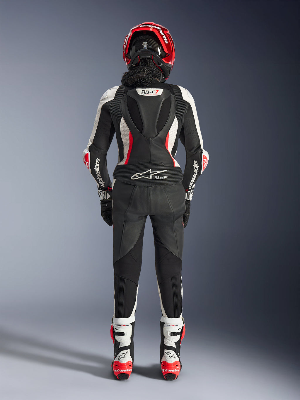 Alpinestars Stella GP-R7 2-Teiler-Lederanzug für Damen, Rückansicht, Schwarz, Weiß und Rot Fluo, mit aerodynamischem Höcker und GP-R7-Branding, Tech-Air Ready-Logo am unteren Rücken, Akkordeon-Stretch-Einsätzen und Alpinestars-Branding auf den Ärmeln, getragen mit passendem Helm und Stiefeln