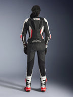 Rückansicht des Alpinestars Stella GP-R7 2-teiligen Lederanzugs, Schwarz, Weiß und Fluo-Rot, mit einem aerodynamischen Höcker samt GP-R7-Branding und Tech-Air Ready-Logo, getragen mit passenden Rennstiefeln und Handschuhen, professionelle Motorradausrüstung für Damen