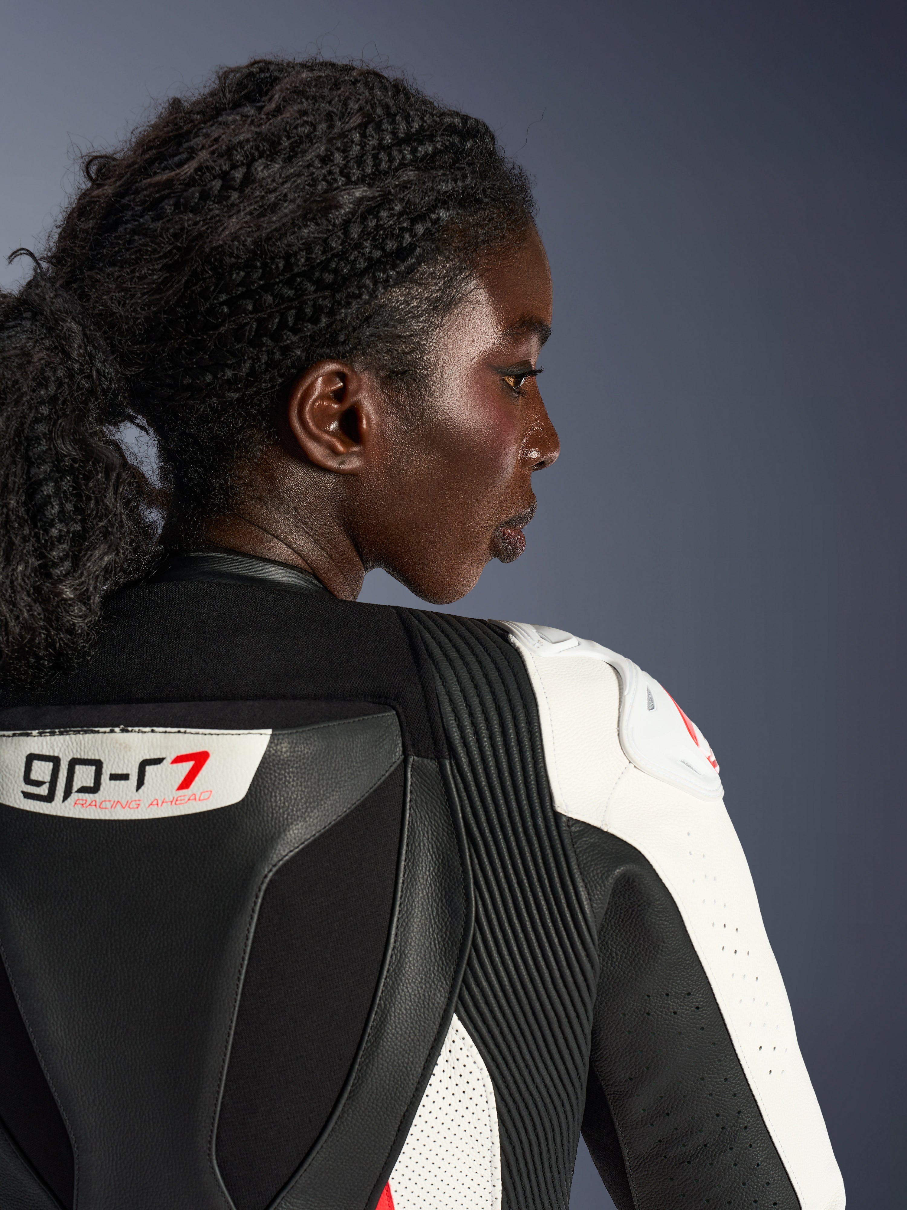 Alpinestars Stella GP-R7 2-Teiler-Lederanzug für Damen, Profil-Nahaufnahme des oberen Rücken- und Schulterbereichs in schwarz-weißem Leder, mit GP-R7 Logo, Akkordeon-Stretch-Einsätzen und weißem Schulterprotektor mit rotem Logo.