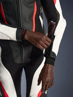 Alpinestars Stella GP-R7 2-Teiler Lederanzug für Damen, Schwarz, Weiß und Fluo-Rot, Nahaufnahme einer Fahrerin beim Justieren des Ärmelreißverschlusses, mit perforierten Ledereinsätzen und Tech-Air-Branding, professionelle Motorrad-Rennausrüstung