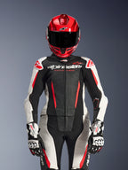 Alpinestars Stella GP-R7 2-Teiler-Lederanzug für Damen, Schwarz, Weiß und Fluo-Rot, mit perforierten Paneelen und 'Racing Ahead'-Branding, roter Helm, weiß-schwarze GP Pro Handschuhe, professionelle Rennsport-Ausrüstung