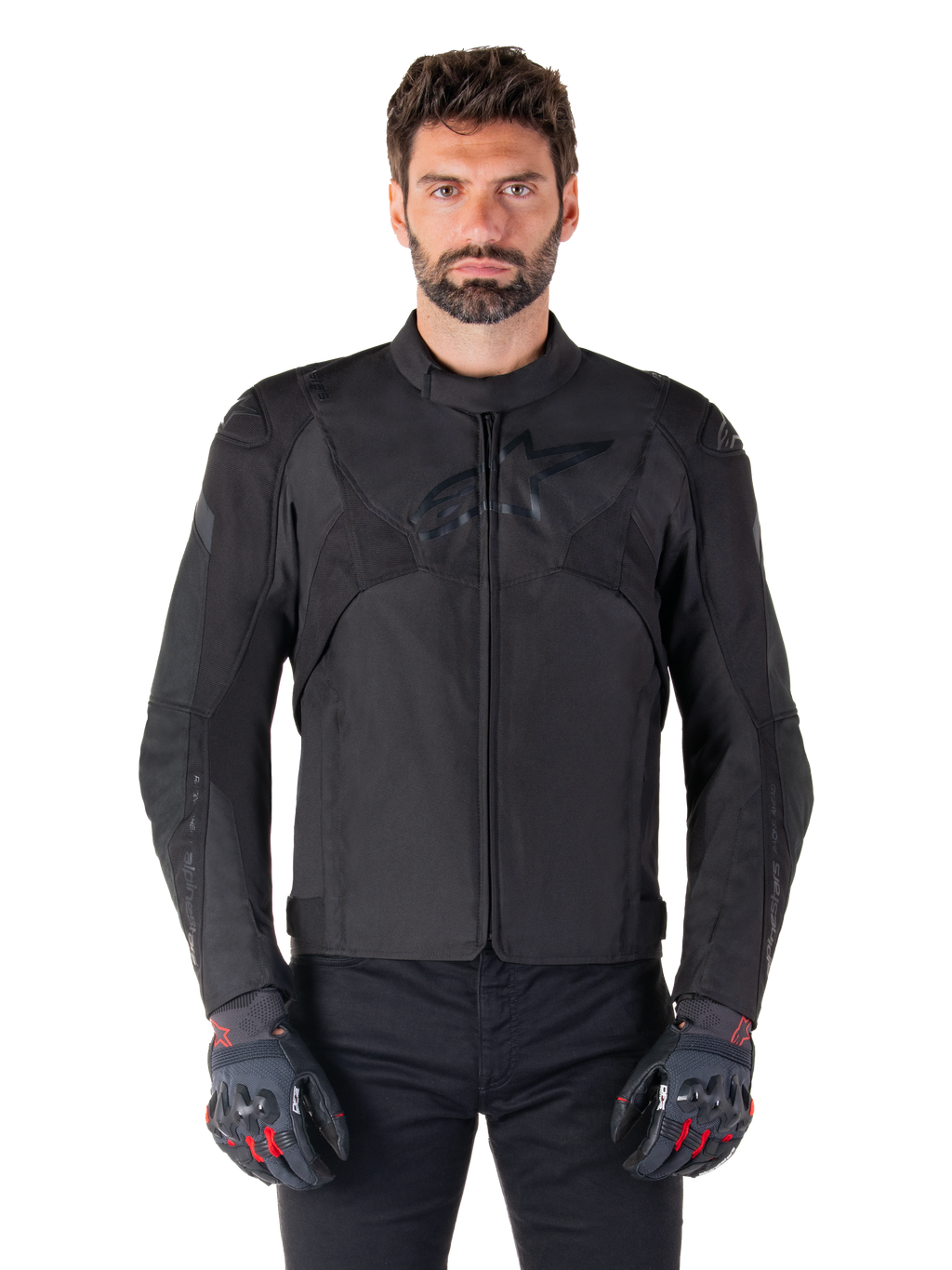 Alpinestars T-Jaws V4 Wasserdichte Jacke, schwarze Motorrad-Sportjacke, getragen von einem Mann mit schwarzen Handschuhen mit roten Akzenten, verstärkte Schultern und Arme, elegantes Design mit dezentem Brustlogo, textile Allwetter-Fahrerausrüstung