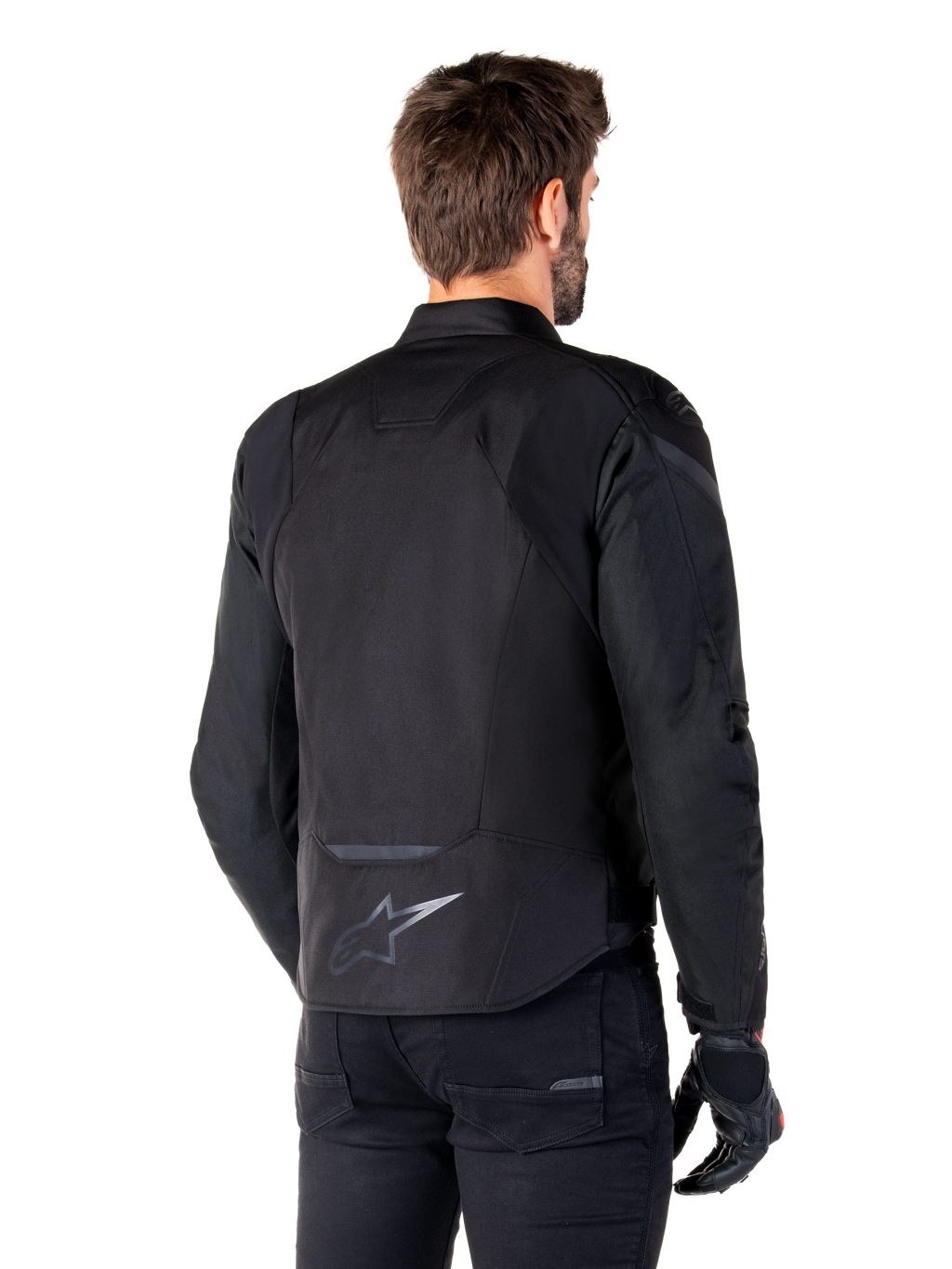 Alpinestars T-Jaws V4 Wasserdichte Jacke, Schwarz, Rückansicht am Modell, mit reflektierendem Alpinestars-Logo am unteren Rücken, verlängerte Rückenpartie für mehr Abdeckung, sportliches Textildesign mit farblich abgestimmten Einsätzen, getragen mit schwarzen Motorradhandschuhen