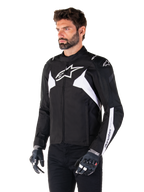 Alpinestars T-Jaws V4 Wasserdichte Jacke, Schwarz und Weiß, getragen von einem Model mit Motorradhandschuhen, mit markanten weißen Alpinestars-Logos und Akzenten, sportliche Textil-Motorradjacke für den Straßeneinsatz